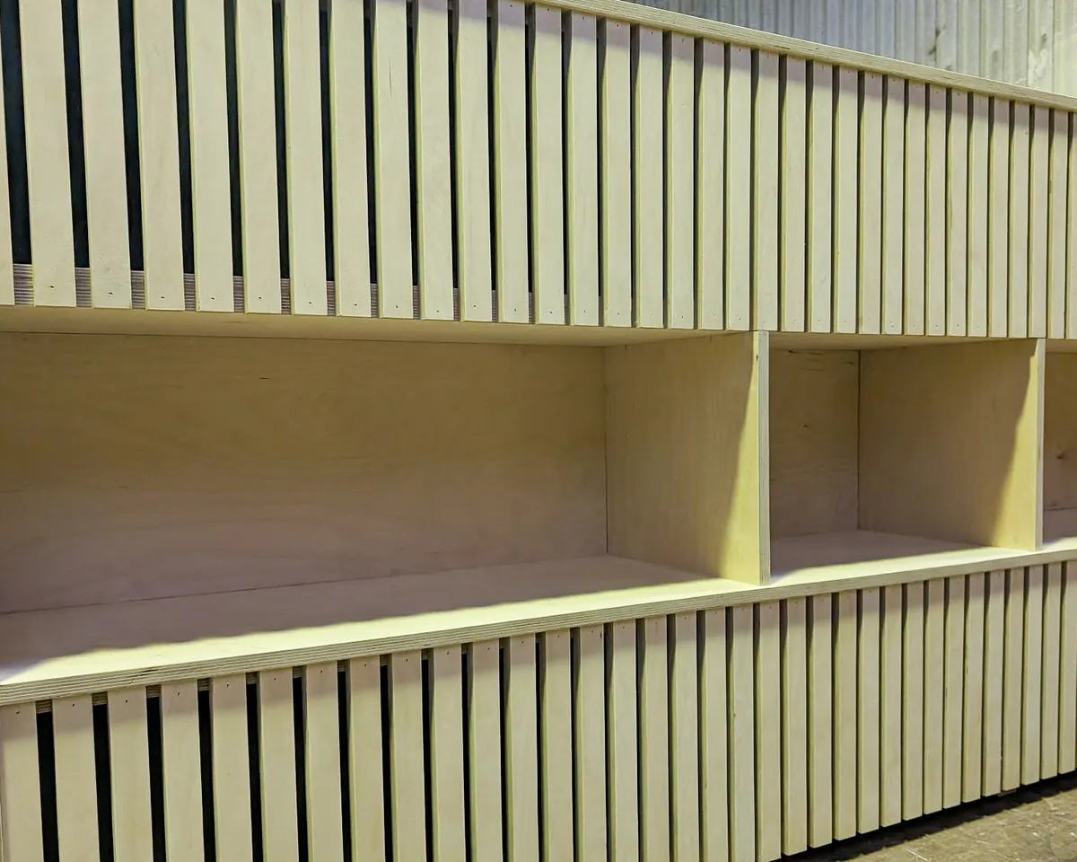 Meuble en bois sur mesure dans un bar à CBD réalisé par Maison Charlet. Ce meuble, élégant et fonctionnel s'intègre parfaitement dans l'ambiance du bar. Il est composé d'un comptoir, d'étagères et de rangements.
